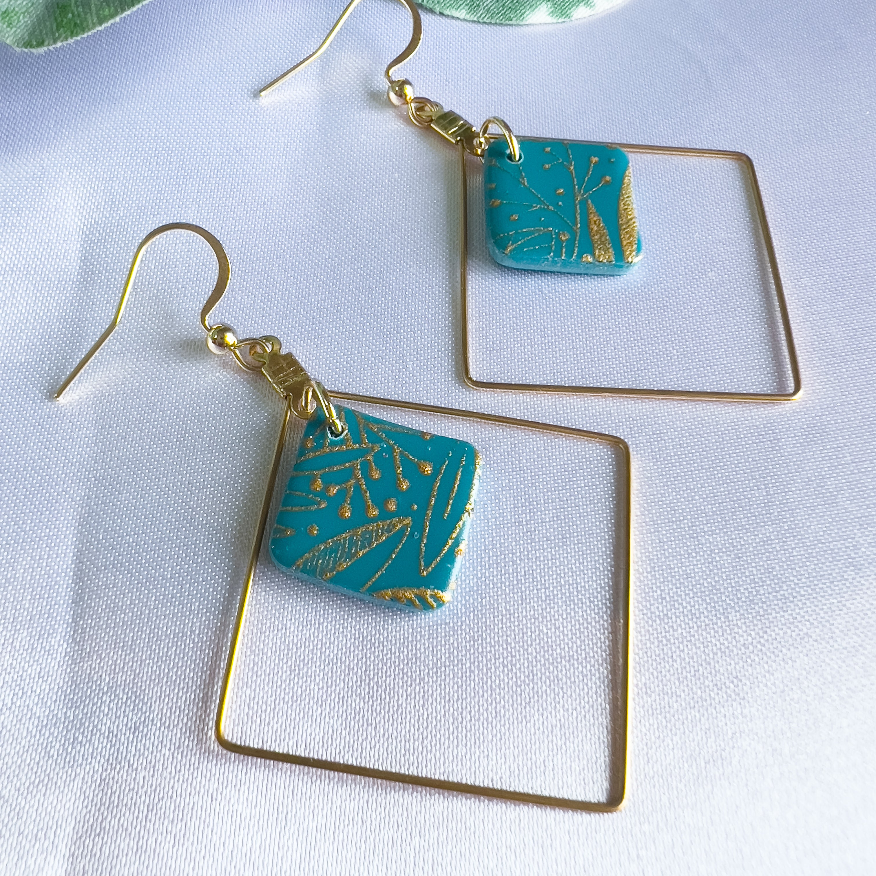 Bijoux, boucles d'oreilles artisanales, créoles carrées en acier inoxydable doré avec pendentif carré suspendu dedans, en argile polymère bleue